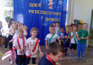 Dwa zespoły dzieci ustawione w rzędach przed konkurencją sportową.